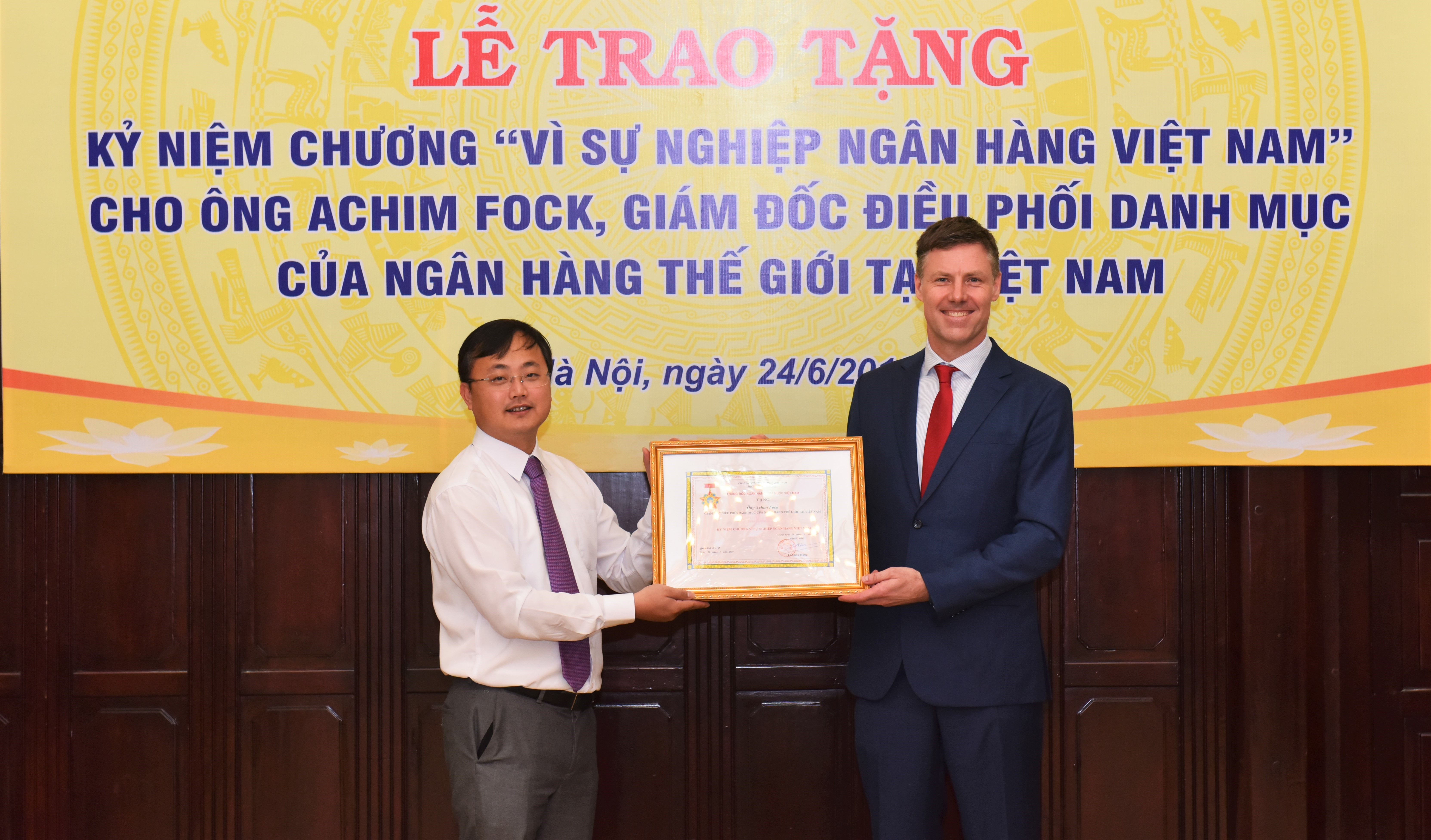Ông Tô Huy Vũ – Vụ trưởng Vụ HTQT NHNN trao tặng bằng khen Thống đốc và Kỷ niệm chương cho Ông Achim Fock - Giám đốc Điều phối danh mục WB