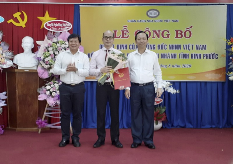 Deputy Governor Dao Minh Tu hands over the SBV’s Appointment Decision to Mr. Bui Huy Tho; Vice Chairman of Binh Phuoc Provincial People's Committee Tran Van Mi presents flowers to congratulate the newly appointed Director of the SBV Binh Phuoc branch
