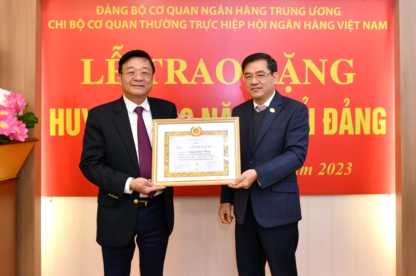Phó Bí thư Đảng ủy Cơ quan NHTƯ Đặng Văn Tuyên - Vụ trưởng Vụ Tổ chức cán bộ (NHNN) trao tặng Huy hiệu cho đảng viên Nguyễn Quốc Hùng
