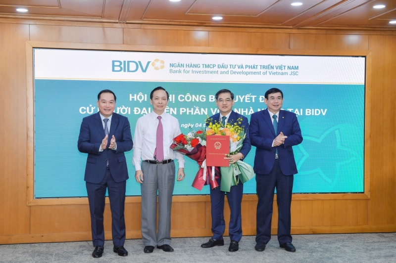 Mr. Dao Minh Tu, SBV First Deputy Governor, and Mr. Ho Xuan Truong, Deputy Secretary of the Party Committee of the Central State-owned Enterprises’ Bloc, hand over the Decision to and congratulated Mr. Dang Van Tuyen.